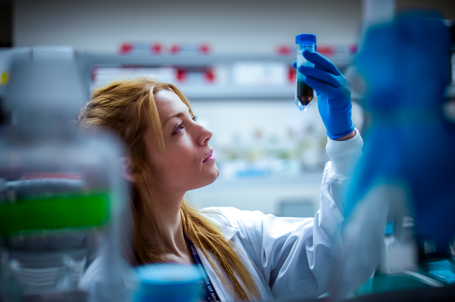 Scientist holding up and looking at a sample in the lab